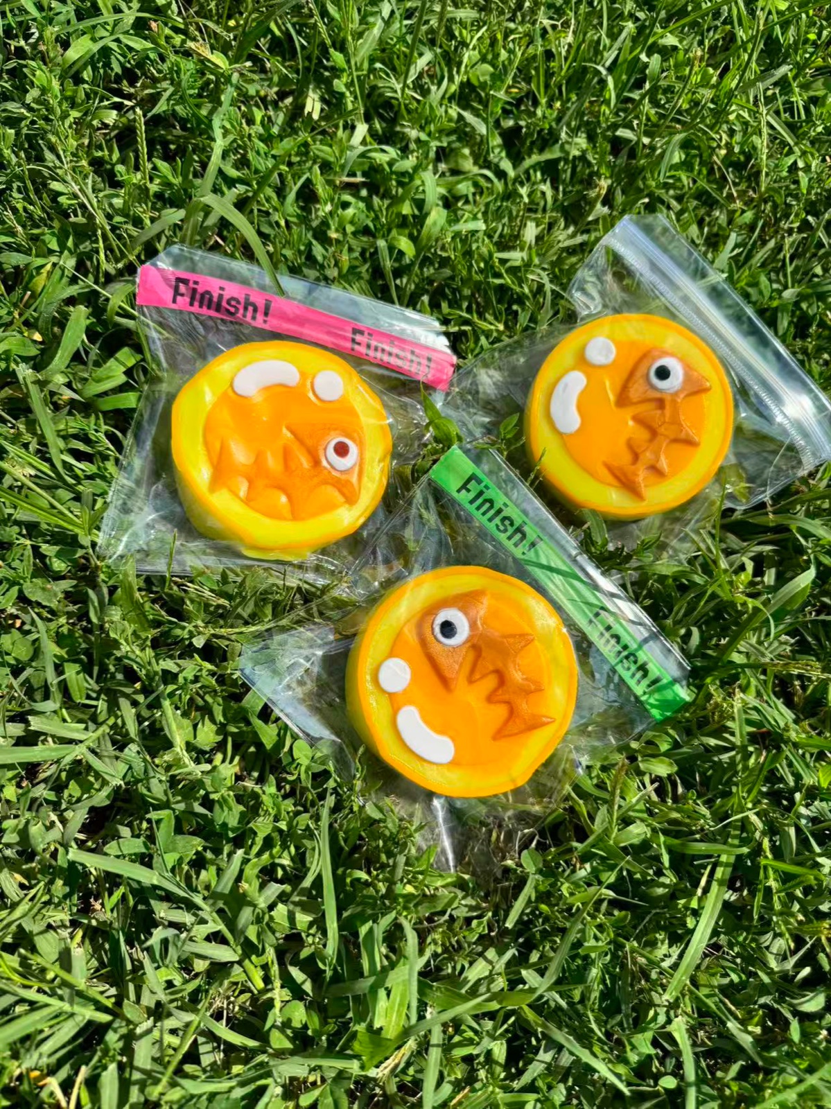 Three finished fish-shaped squeeze toys photographed outdoors